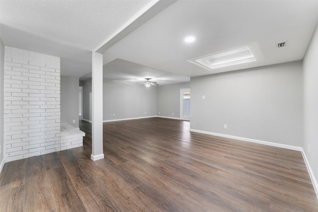 basement with ceiling fan, dark wood-type flooring, and a textured ceiling