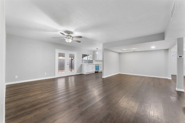 unfurnished living room with ceiling fan, dark hardwood / wood-style flooring, a textured ceiling, and french doors