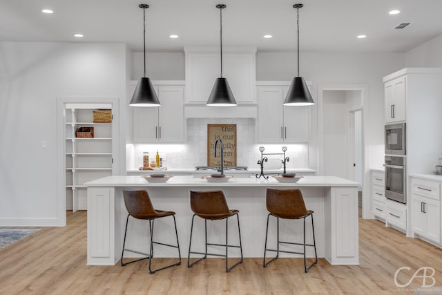 kitchen featuring a center island with sink, white cabinetry, and stainless steel appliances