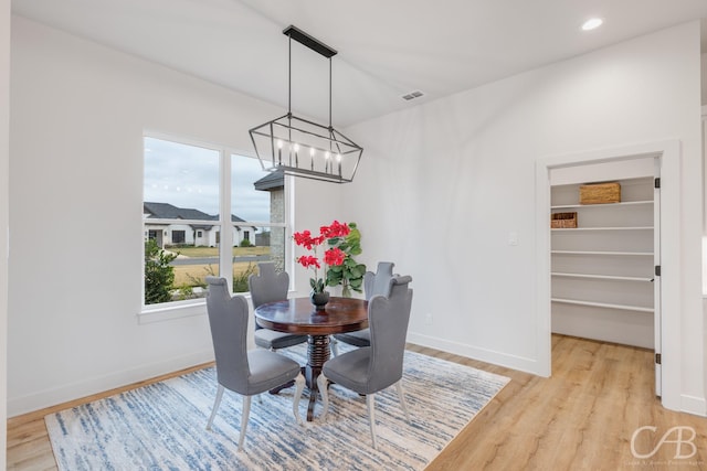 dining area with light hardwood / wood-style floors, an inviting chandelier, and a healthy amount of sunlight