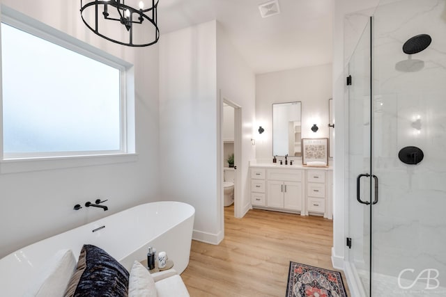 full bathroom featuring an inviting chandelier, hardwood / wood-style floors, toilet, vanity, and independent shower and bath