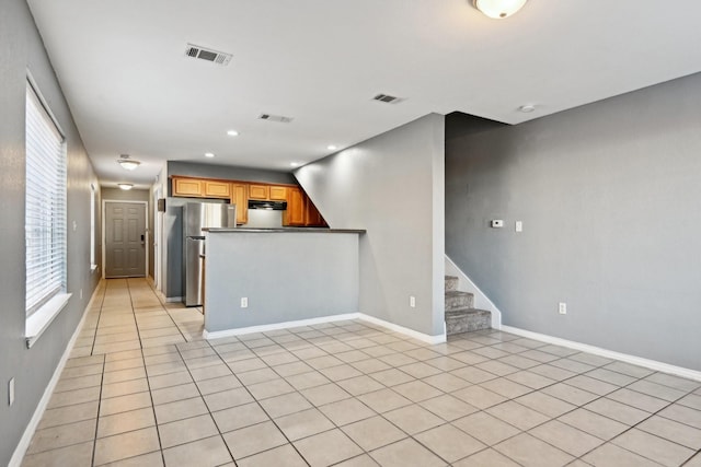 kitchen with a wealth of natural light, stainless steel fridge, and light tile patterned floors