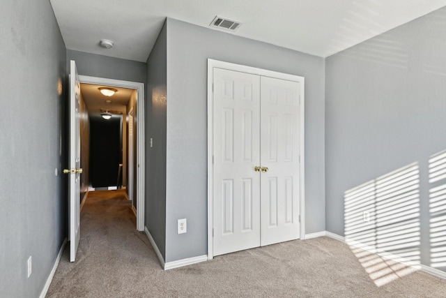 unfurnished bedroom with light carpet and a closet