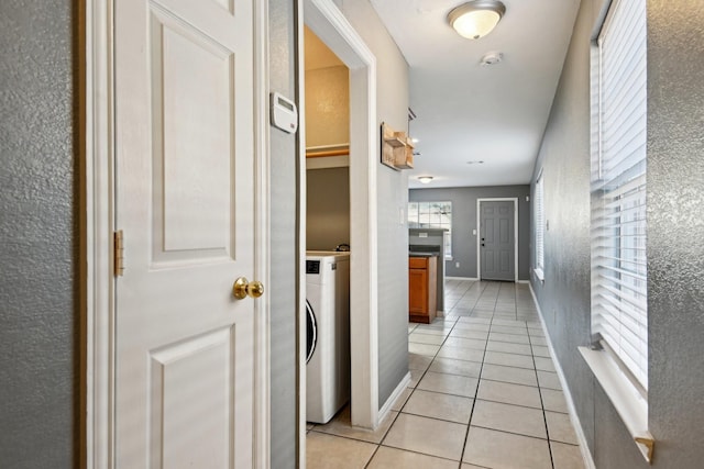 corridor with light tile patterned floors and washer / dryer