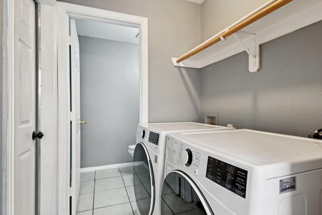 clothes washing area with light tile patterned flooring and washer and clothes dryer