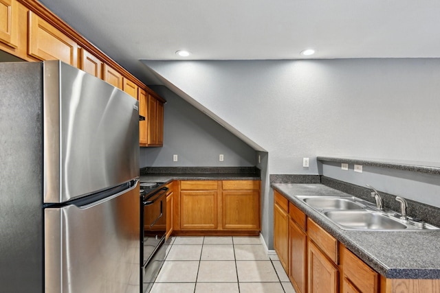 kitchen featuring dark countertops, freestanding refrigerator, black / electric stove, a sink, and light tile patterned flooring