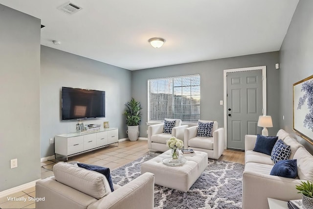 living area featuring light tile patterned floors, visible vents, and baseboards