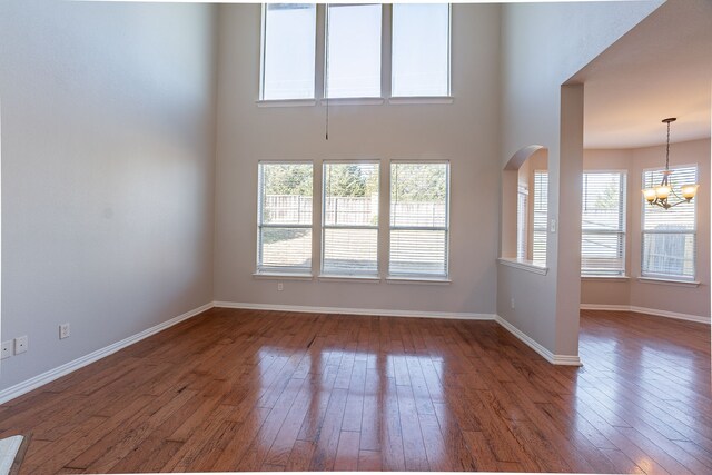 empty room with dark hardwood / wood-style flooring and a chandelier