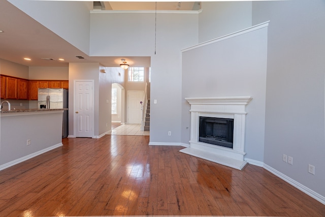 unfurnished living room with wood-type flooring and a high ceiling