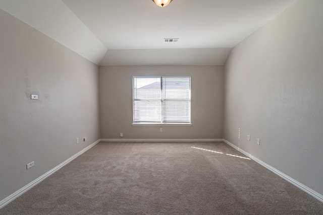 carpeted spare room featuring vaulted ceiling