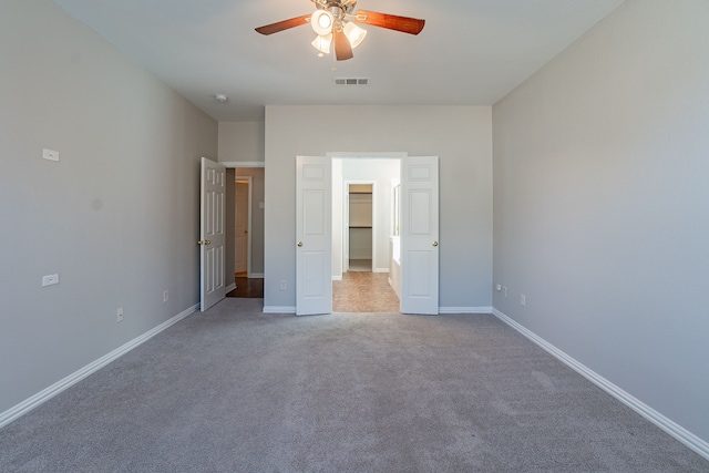 unfurnished bedroom featuring a spacious closet, light carpet, and ceiling fan