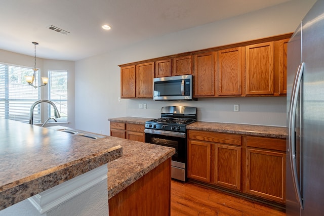 kitchen featuring appliances with stainless steel finishes, sink, dark wood-type flooring, and decorative light fixtures