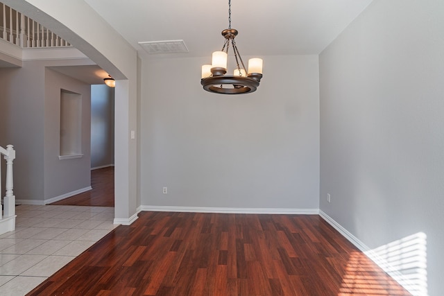 unfurnished room with hardwood / wood-style flooring and a chandelier