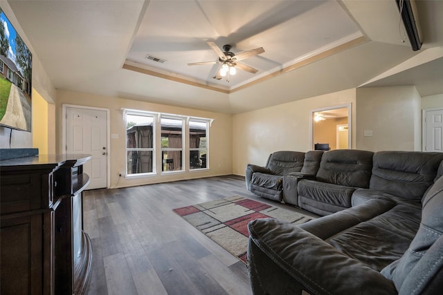 living room with dark hardwood / wood-style flooring, a raised ceiling, and ceiling fan