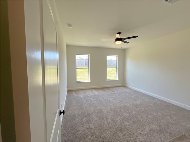 carpeted spare room featuring visible vents, a ceiling fan, and baseboards