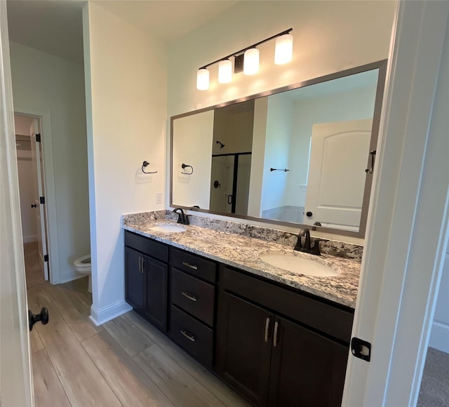 full bathroom with toilet, a sink, double vanity, and a stall shower