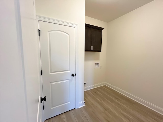 washroom with light wood-style flooring, baseboards, washer hookup, and cabinet space