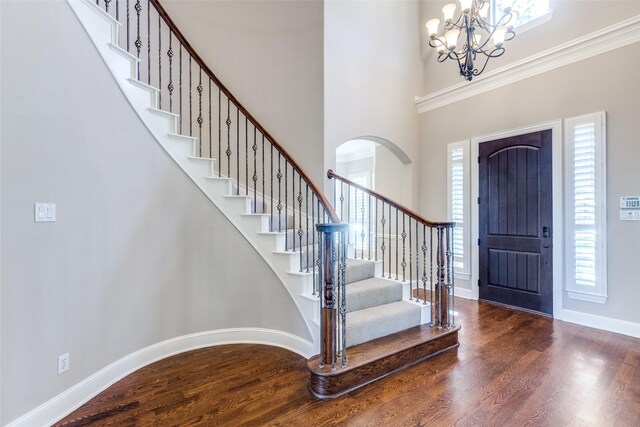 foyer entrance with a healthy amount of sunlight, dark hardwood / wood-style flooring, crown molding, and a chandelier