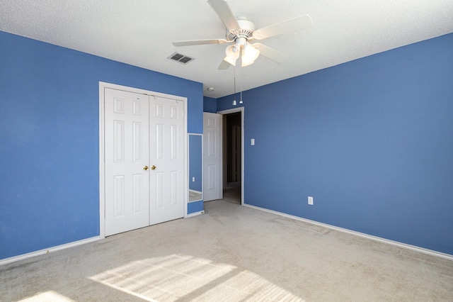 unfurnished bedroom featuring ceiling fan, light carpet, a closet, and a textured ceiling