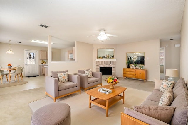 carpeted living room featuring ceiling fan and a brick fireplace