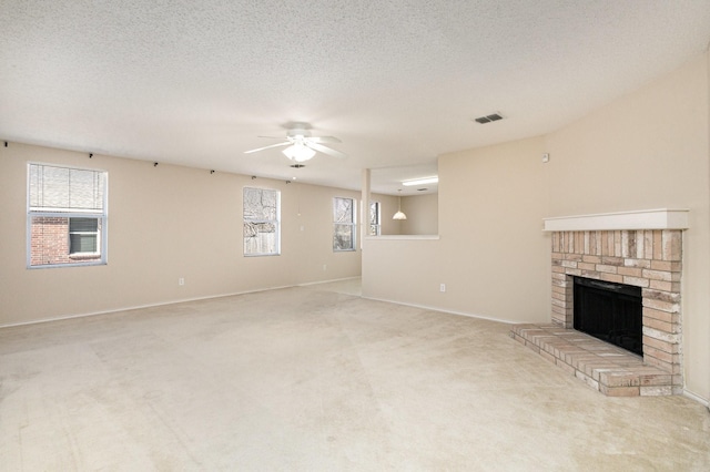 unfurnished living room with ceiling fan, light colored carpet, a textured ceiling, and a fireplace