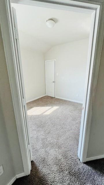 corridor featuring carpet floors and vaulted ceiling