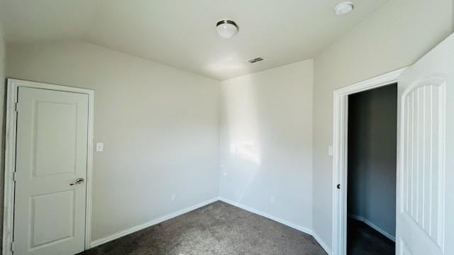 spare room with dark carpet and vaulted ceiling