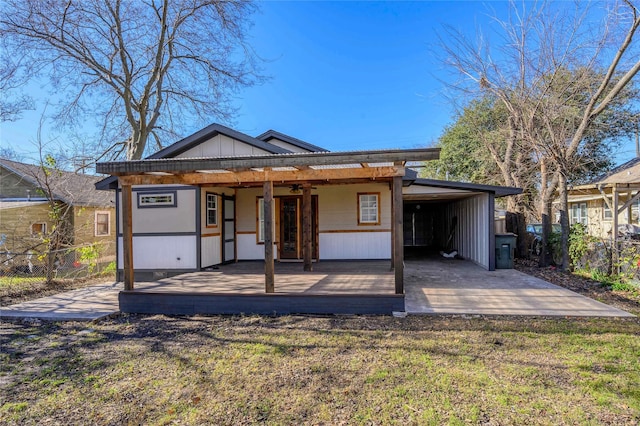 rear view of property featuring a carport, a deck, and a lawn