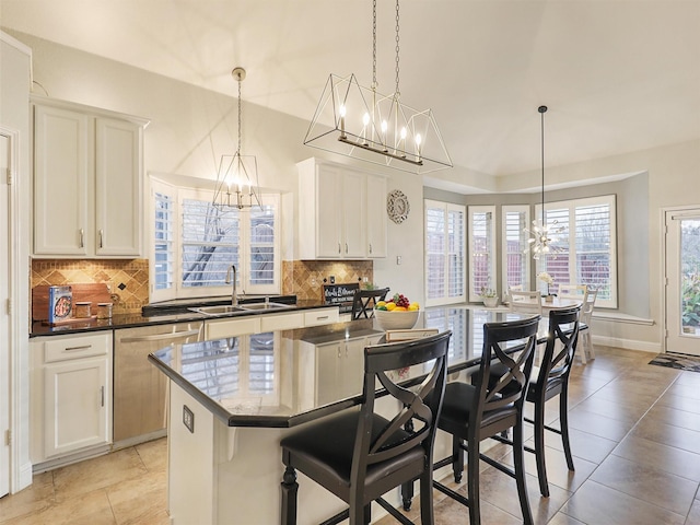 kitchen featuring stainless steel dishwasher, backsplash, sink, and an island with sink