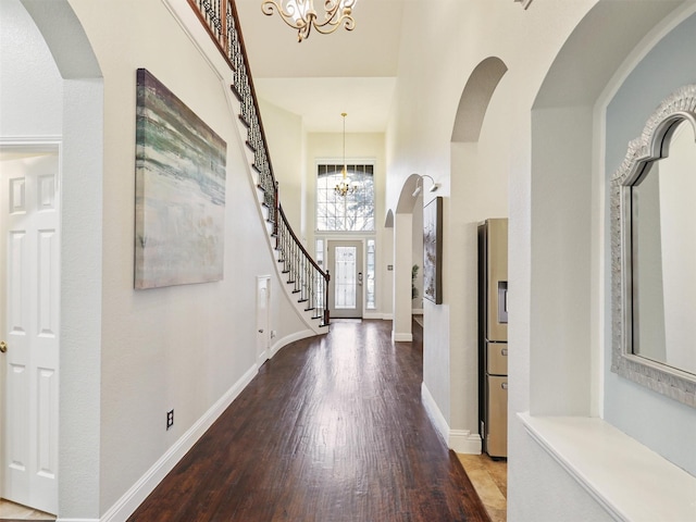 foyer with an inviting chandelier, wood-type flooring, and a high ceiling