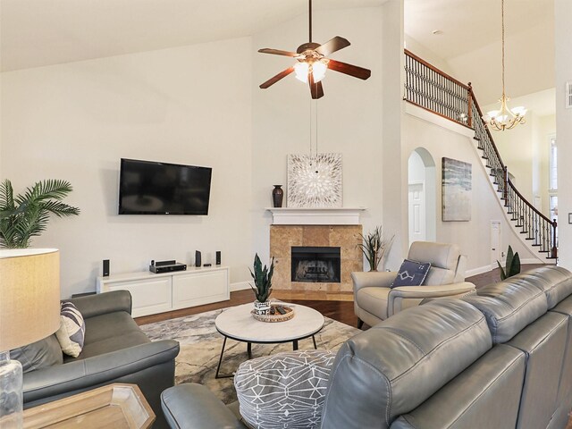 living room with a fireplace, wood-type flooring, ceiling fan with notable chandelier, and high vaulted ceiling