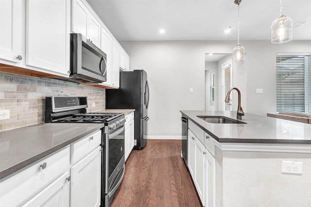 kitchen featuring white cabinetry, sink, stainless steel appliances, and a center island with sink