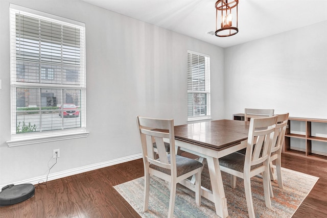 dining space featuring dark wood-type flooring and a chandelier