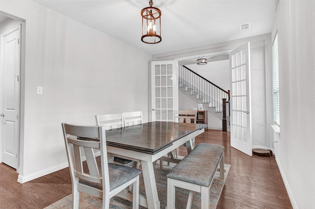 dining room with an inviting chandelier, dark hardwood / wood-style floors, and french doors