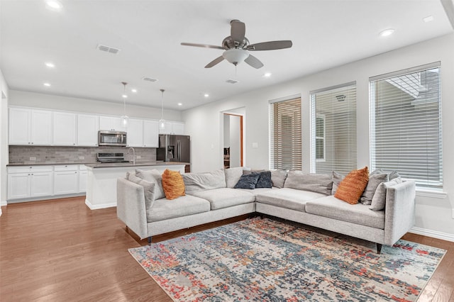 living room featuring sink, light hardwood / wood-style flooring, and ceiling fan