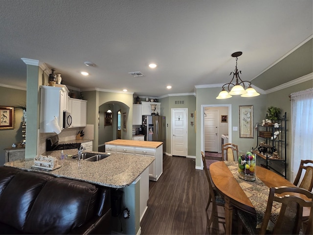 kitchen with pendant lighting, sink, butcher block counters, stainless steel appliances, and white cabinets