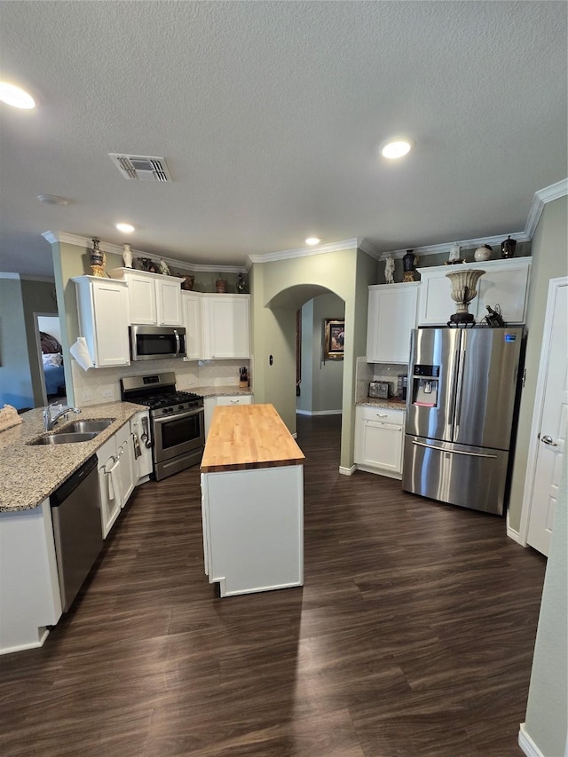 kitchen with dark wood-type flooring, sink, white cabinetry, appliances with stainless steel finishes, and kitchen peninsula