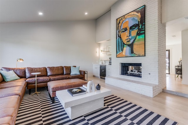 living room with a fireplace, beverage cooler, and light hardwood / wood-style flooring