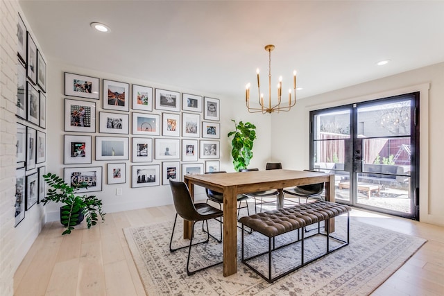 dining space featuring light wood-type flooring, french doors, and a chandelier