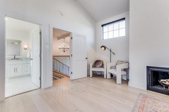 interior space featuring sink, a chandelier, a fireplace, light hardwood / wood-style floors, and lofted ceiling