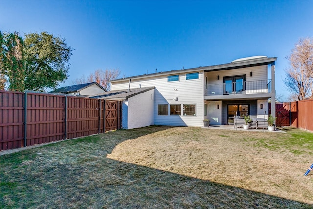 back of property with a yard, a balcony, and a patio area