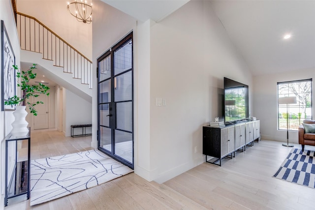 foyer entrance with a notable chandelier, light hardwood / wood-style floors, and high vaulted ceiling