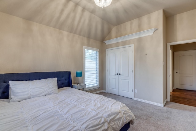 carpeted bedroom featuring a closet, vaulted ceiling, and a notable chandelier