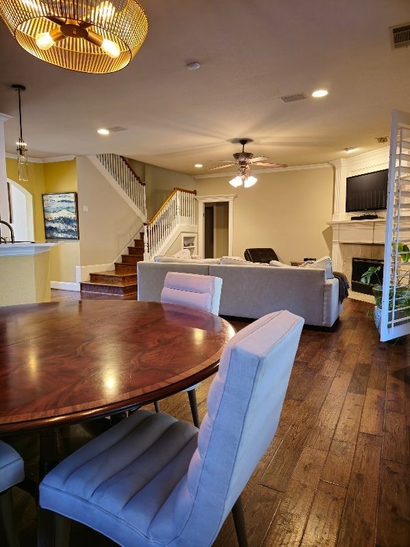 dining space featuring ceiling fan, wood-type flooring, and a tiled fireplace