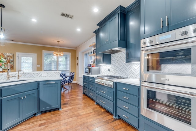 kitchen with light wood-type flooring, backsplash, stainless steel appliances, blue cabinets, and decorative light fixtures