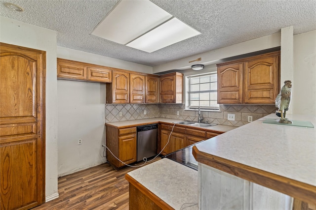 kitchen with sink, tasteful backsplash, a textured ceiling, stainless steel dishwasher, and dark hardwood / wood-style floors