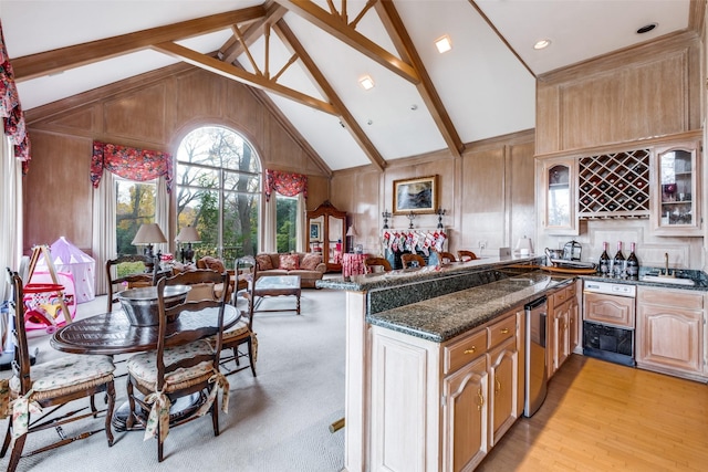 kitchen featuring beamed ceiling, high vaulted ceiling, wood walls, and dark stone countertops