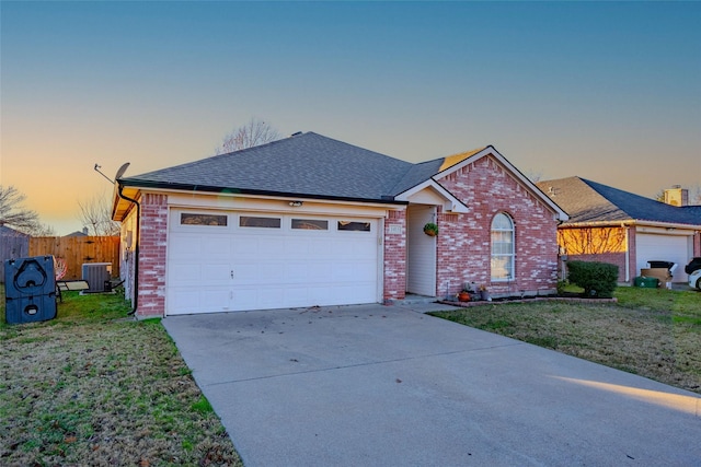 ranch-style house with central AC unit, a garage, and a yard