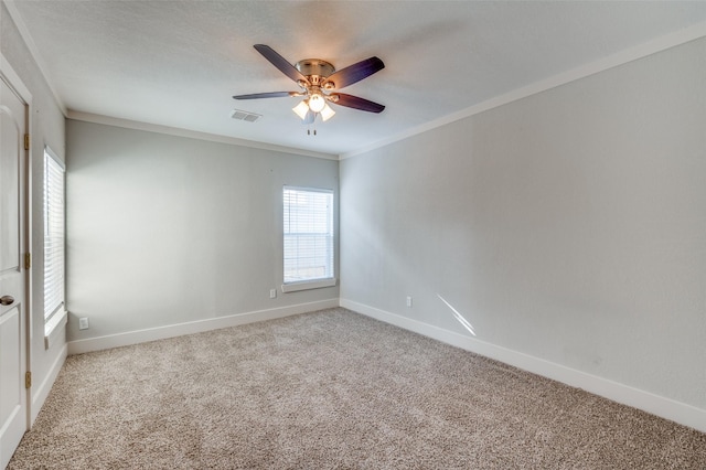 carpeted spare room featuring a wealth of natural light, ceiling fan, and ornamental molding