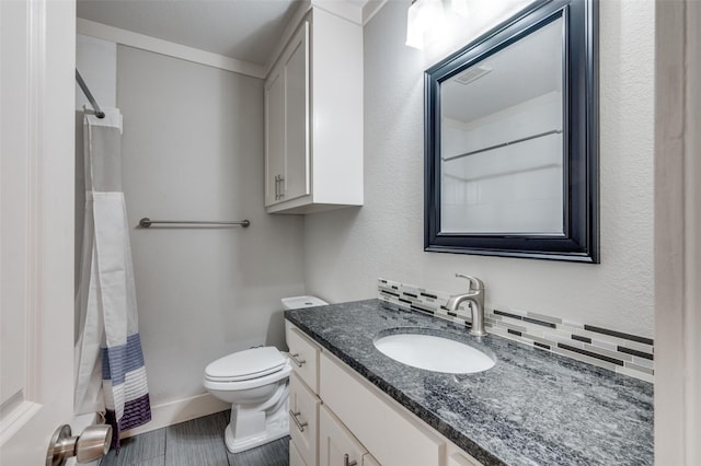 bathroom featuring vanity, toilet, walk in shower, and tasteful backsplash